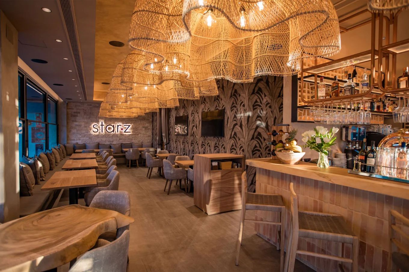 The bar at Starz Marbella, with warm brick, oak tables and rattan lighting