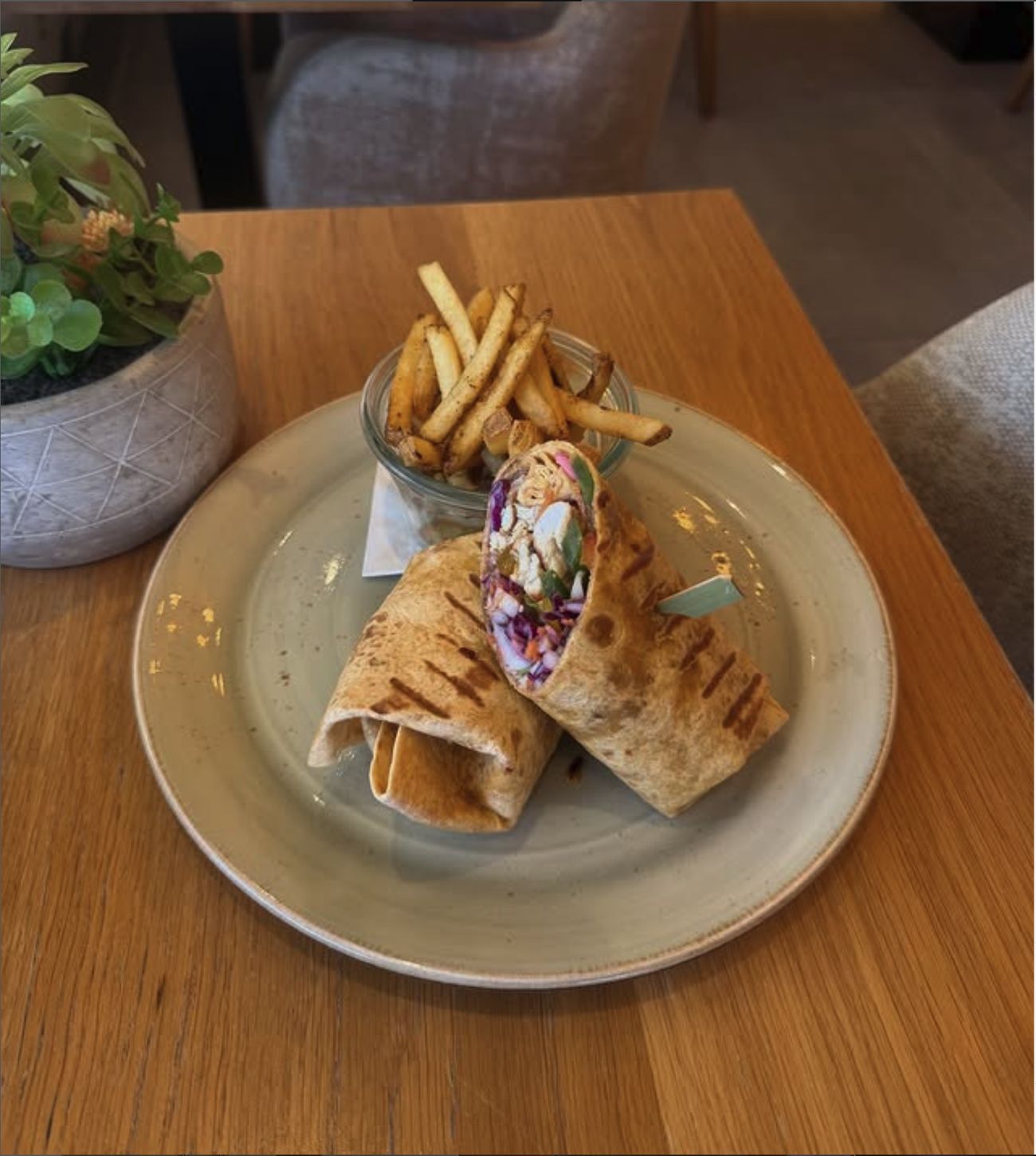A grilled wrap cut open, served with a jar of fries